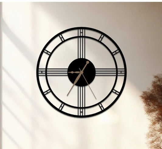 Large black wall clock on a white wall with a wooden bench and decorative plant in the foreground.